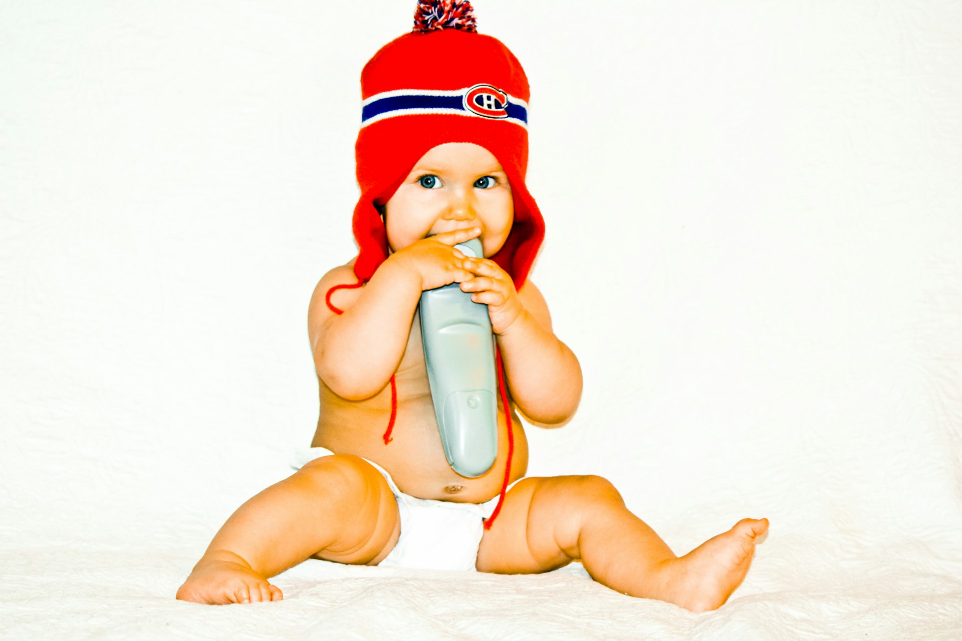 A baby in a red hat holding a toothbrush